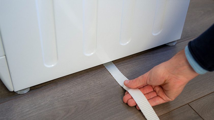 Kéo dây đeo dưới máy giặt và giữ dây đeo ở giữa.