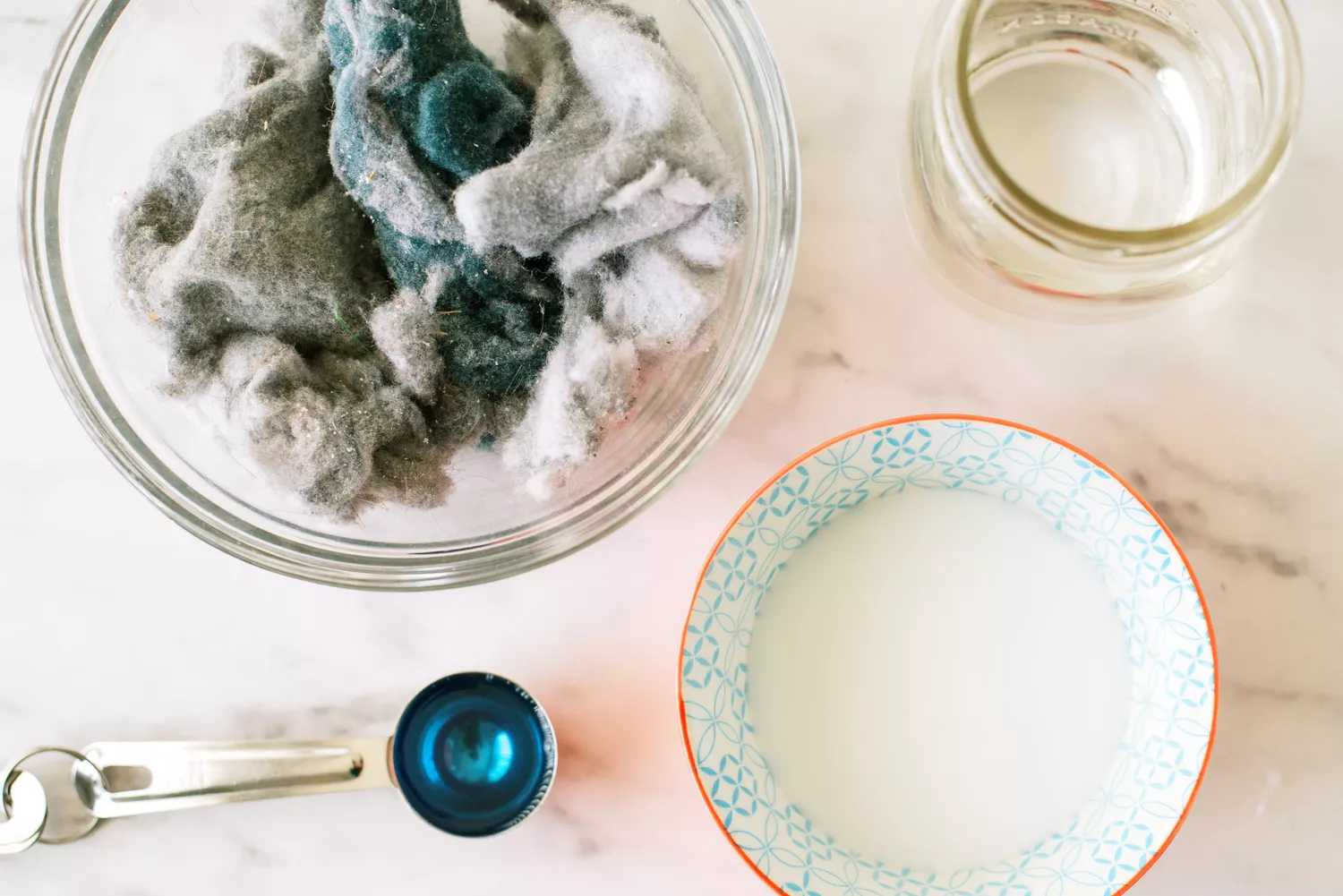 Máy sấy xơ vải trong bát thủy tinh bên cạnh thìa keo rửa chén và cốc keo trắng